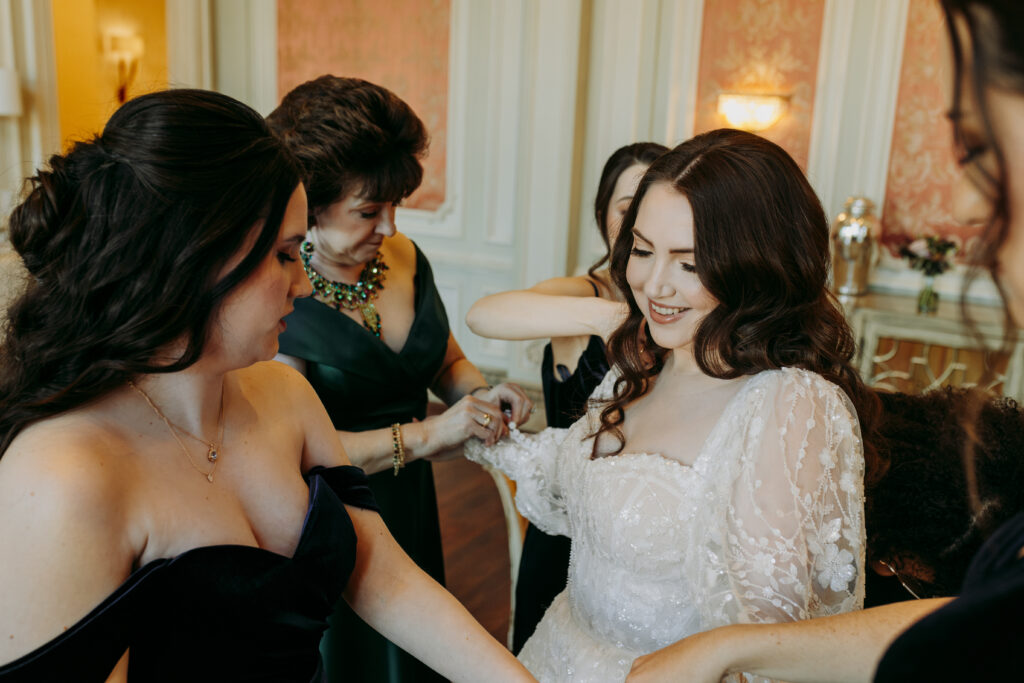 Bride sitting and getting ready with assistance from mother of bride and bridesmaids at The Olana in the bridal suite

