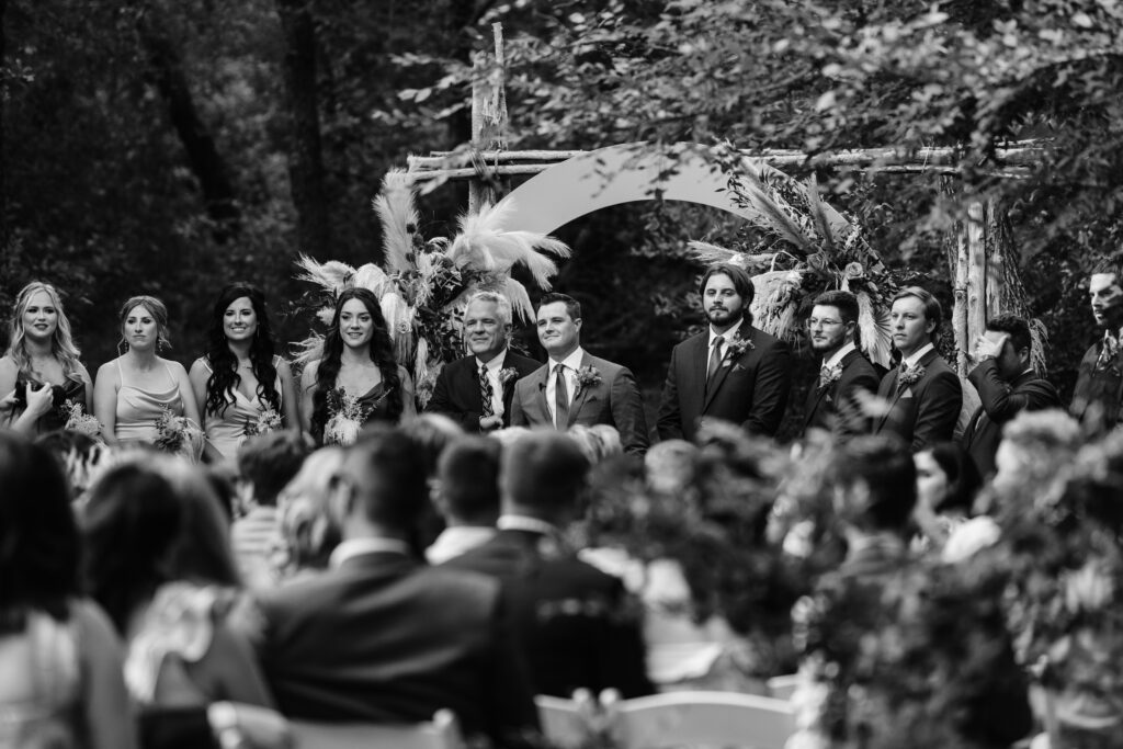 Groom waits at front of ceremony aisle with Groom's party, excitedly waiting for bride to walk down